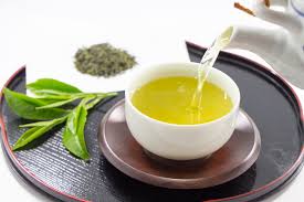無料素材指示：食後に温かい緑茶を飲む女性。笑顔でくつろぎながらお茶を飲む様子の写真。